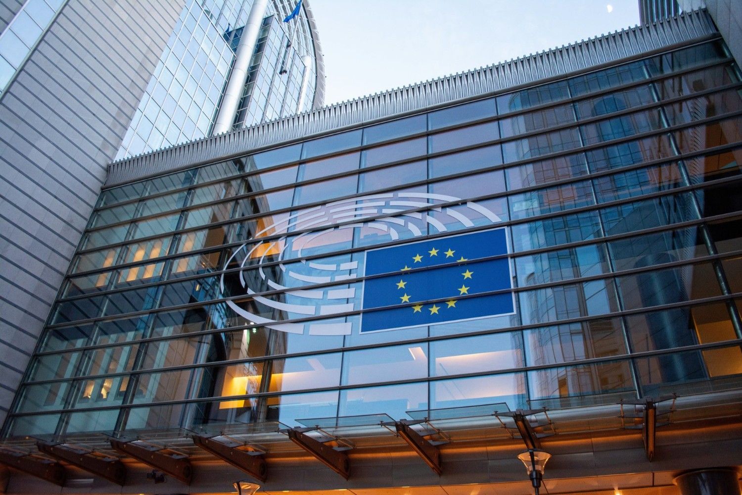 La bandera de la Unión Europea reflejada en el cristal de un edificio moderno.